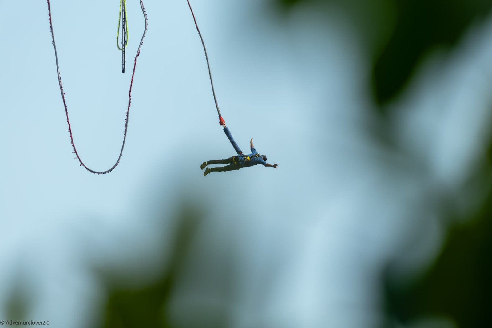 Bungee jumper free falling against the sky above the Ganga gorge in Rishikesh