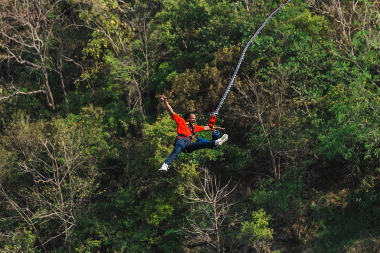 Bungee jumper stretching arms wide during the free fall over the Ganga gorge