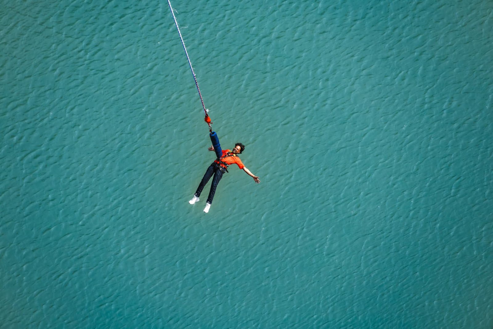Bungee jumper suspended on the cord over the turquoise Ganga waters in Rishikesh
