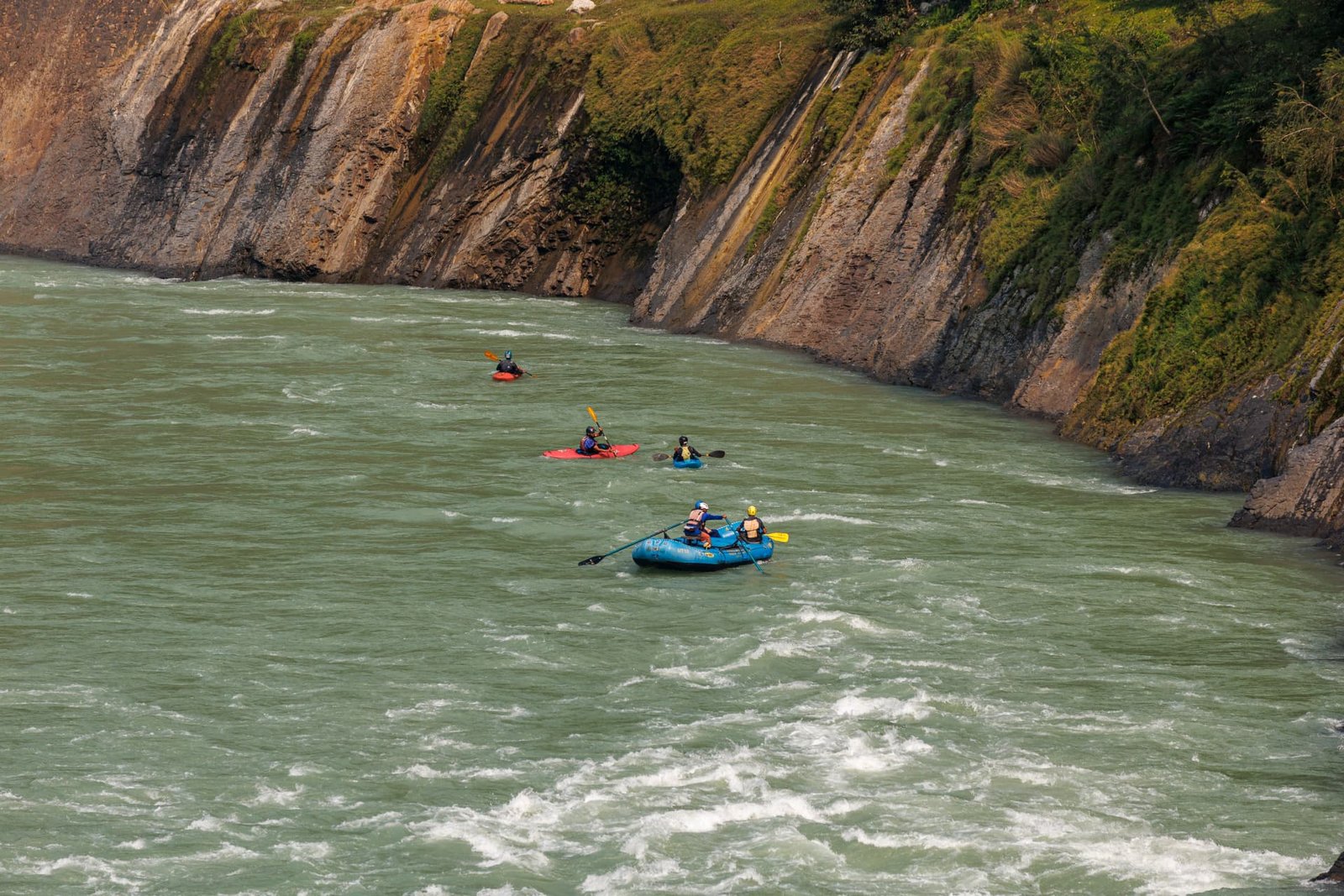 Rafting crew paddling past the cliffs of the Ganga gorge near Shivpuri, Rishikesh